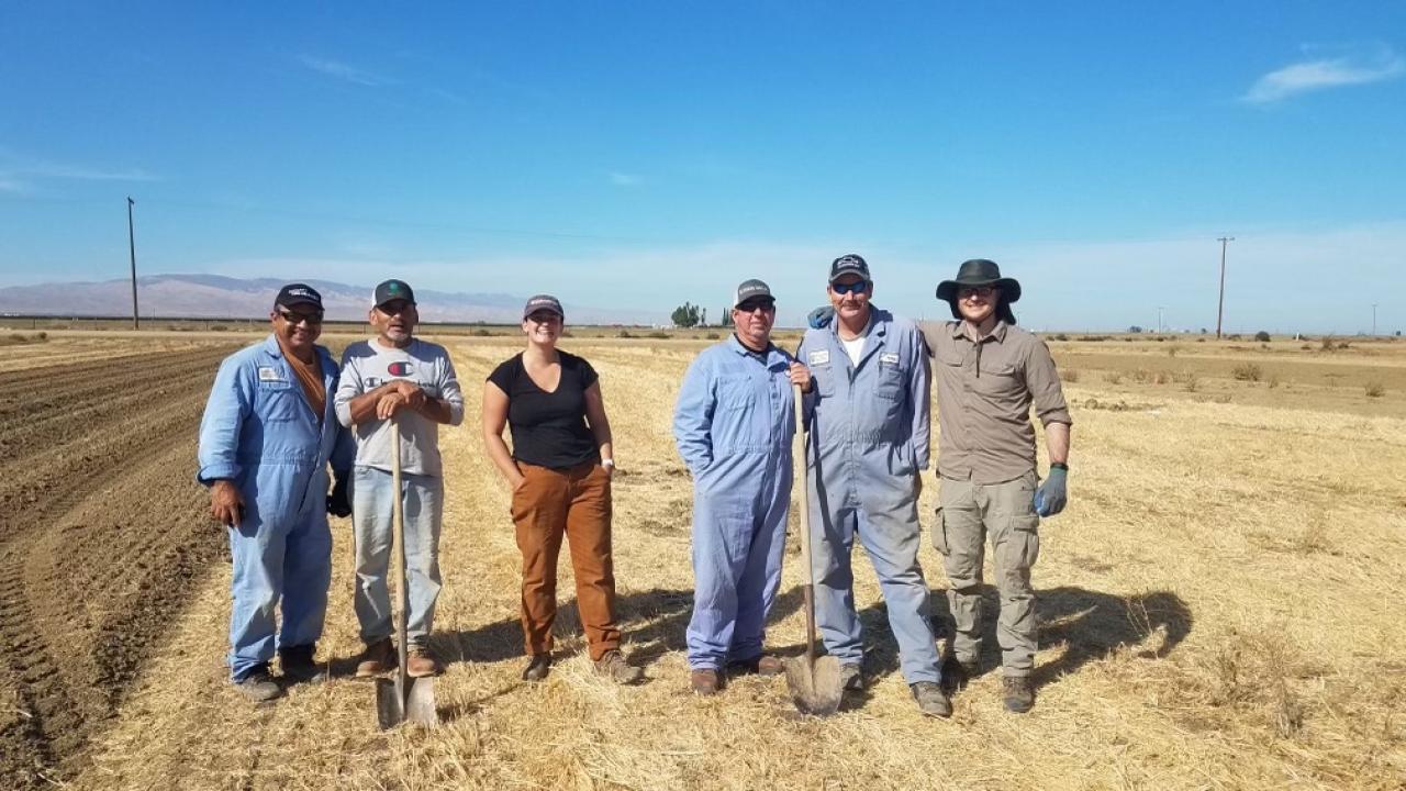six people stand in field smiling at camera 
